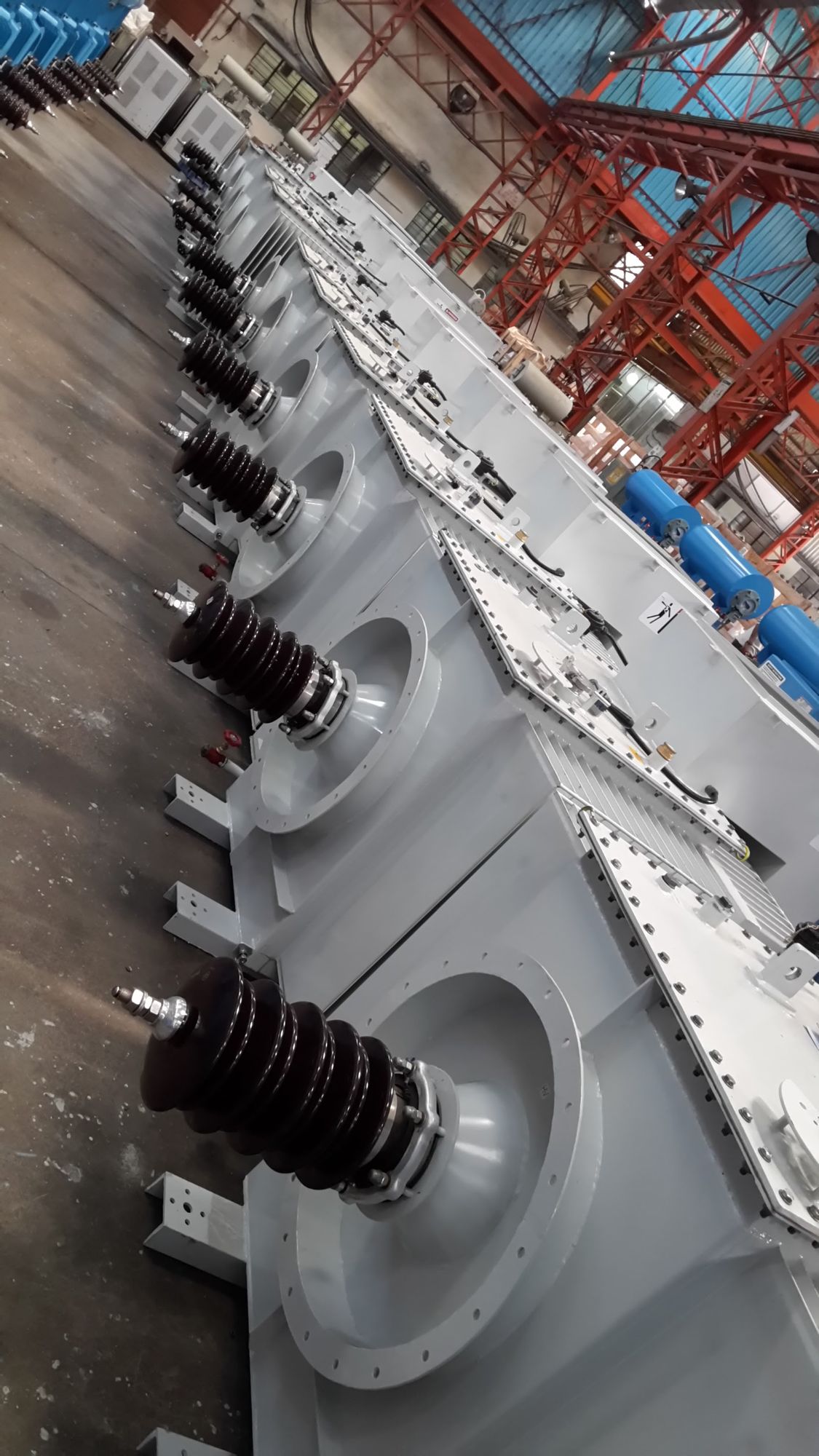 Row of ESP transformer rectifier sets with high-voltage bushings on the assembly floor