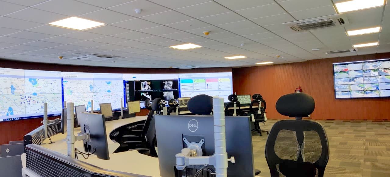 Command centre video wall displaying maps, dashboards and camera feeds in front of operator desks
