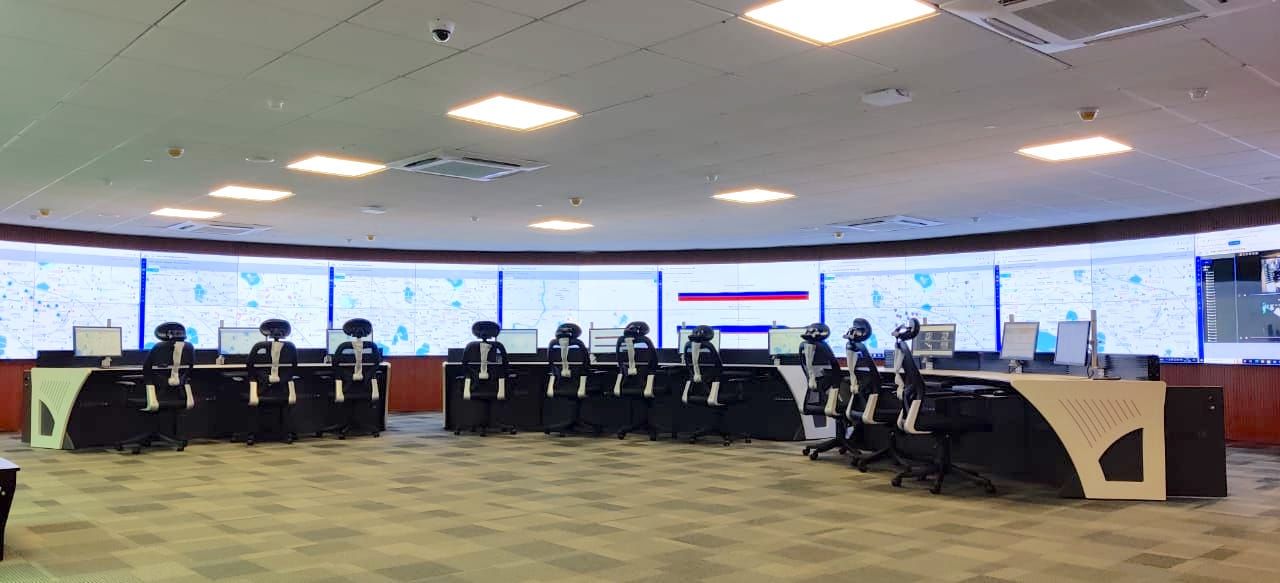 Integrated command and control centre with a curved video wall showing city maps and camera feeds above operator consoles