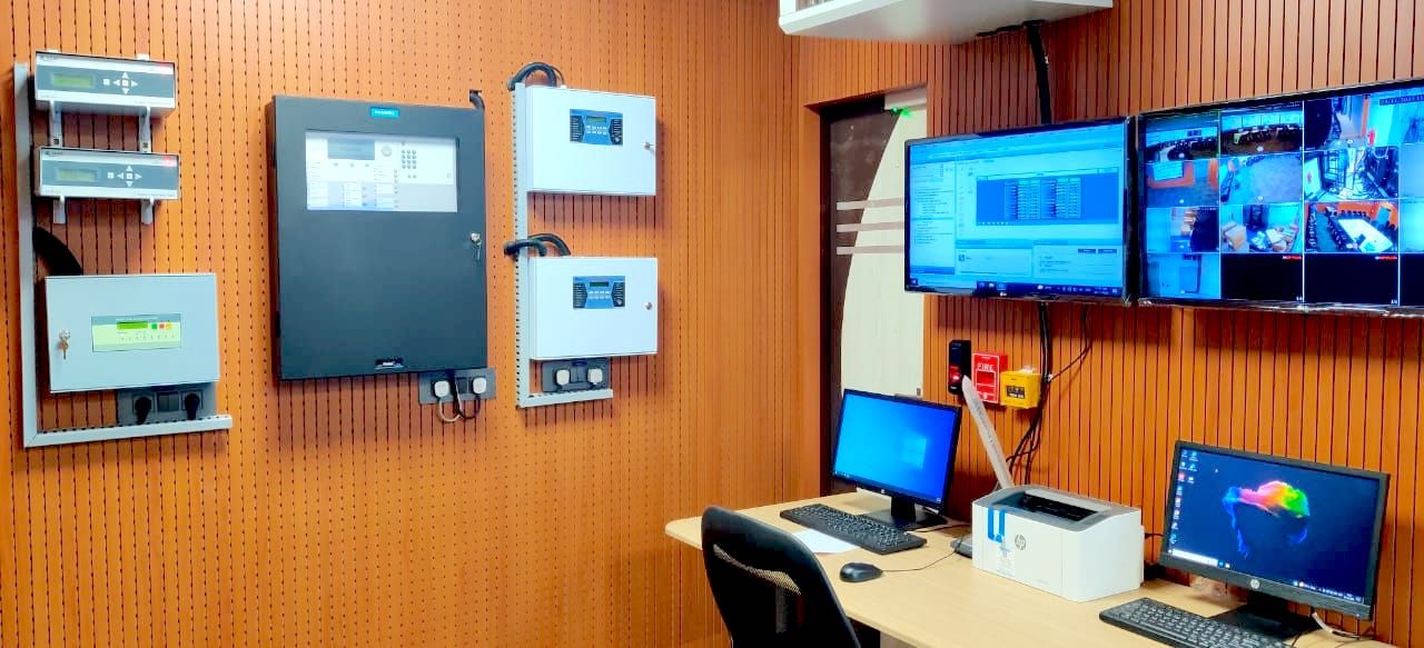 Wall mounted fire detection and system panels beside the operator desk and display wall