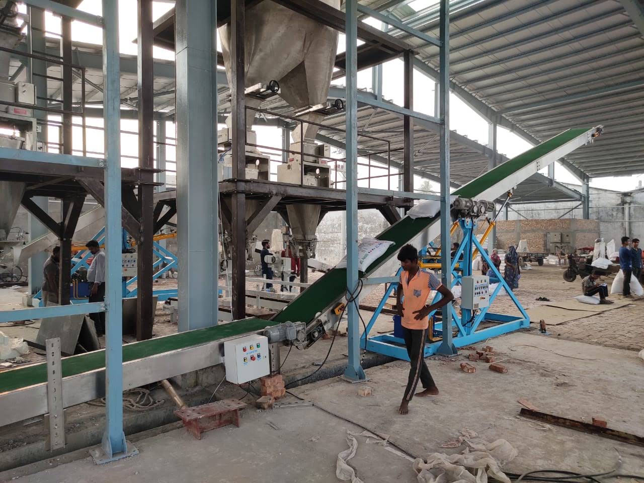 Finished bag conveyor carrying stitched bags away from the bagging stations