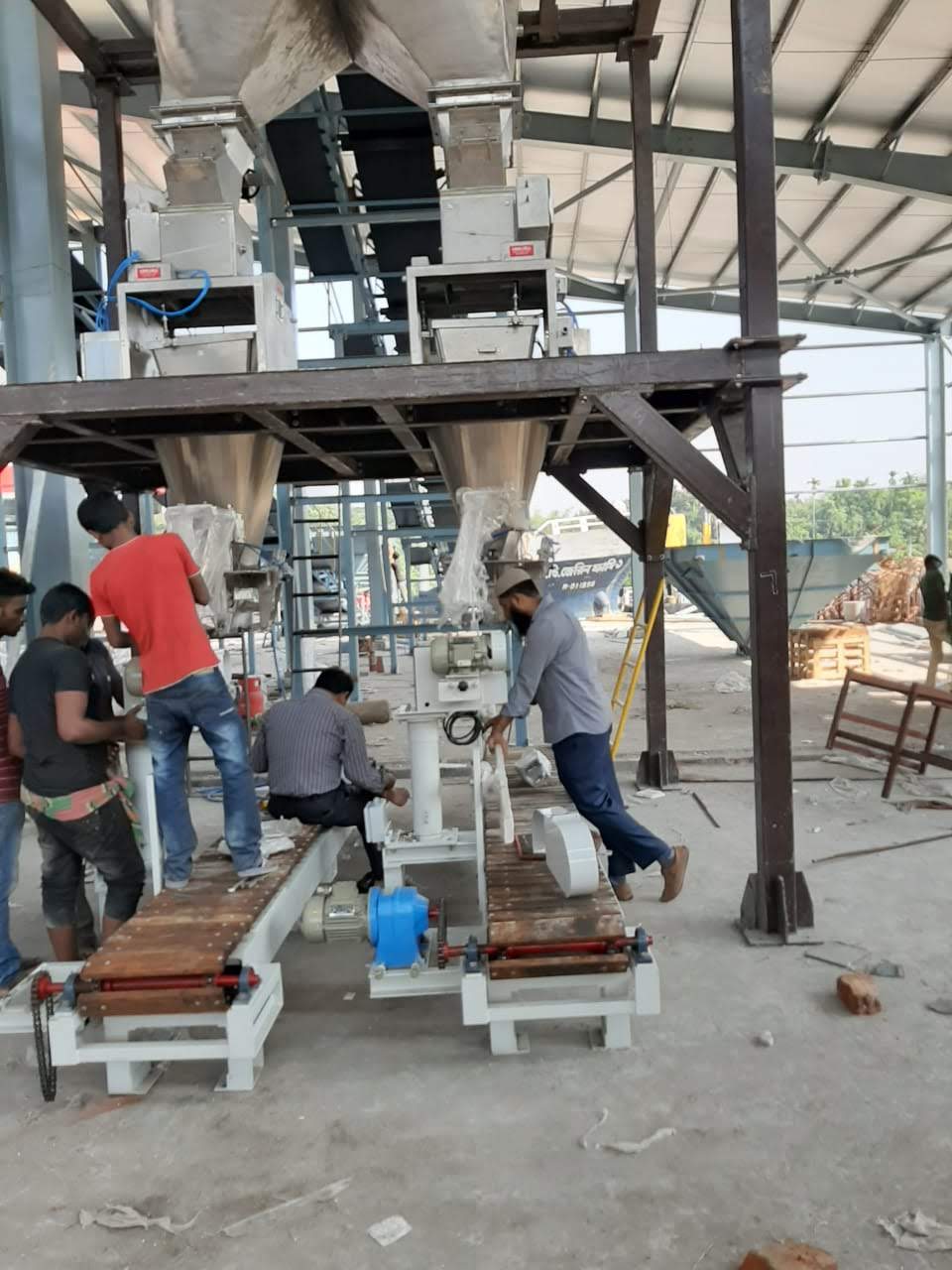Operators at the bagging stations of an installed line with the discharge conveyors in front