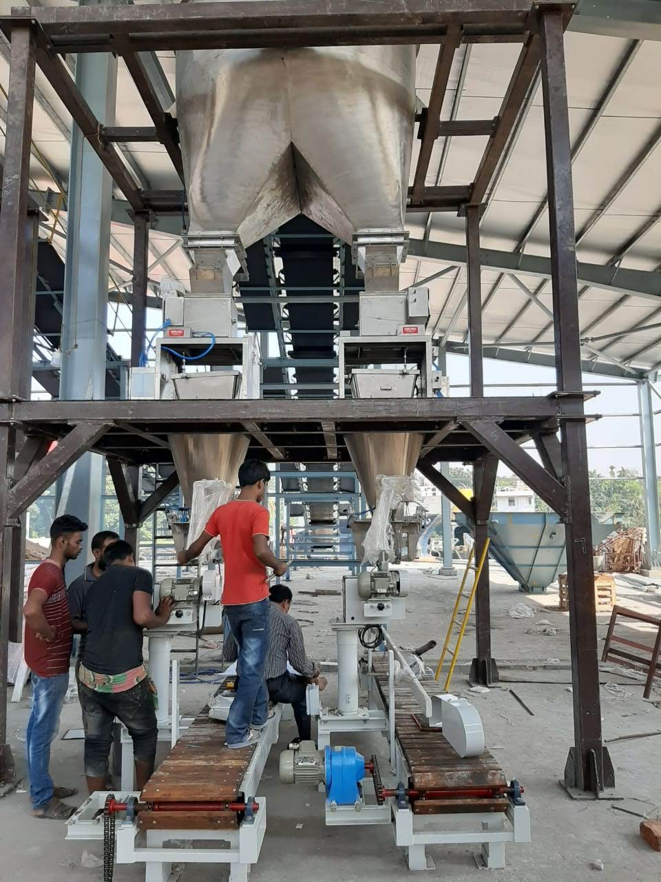 Automatic bagging machines mounted below the weigh hoppers of a bulk bagging line