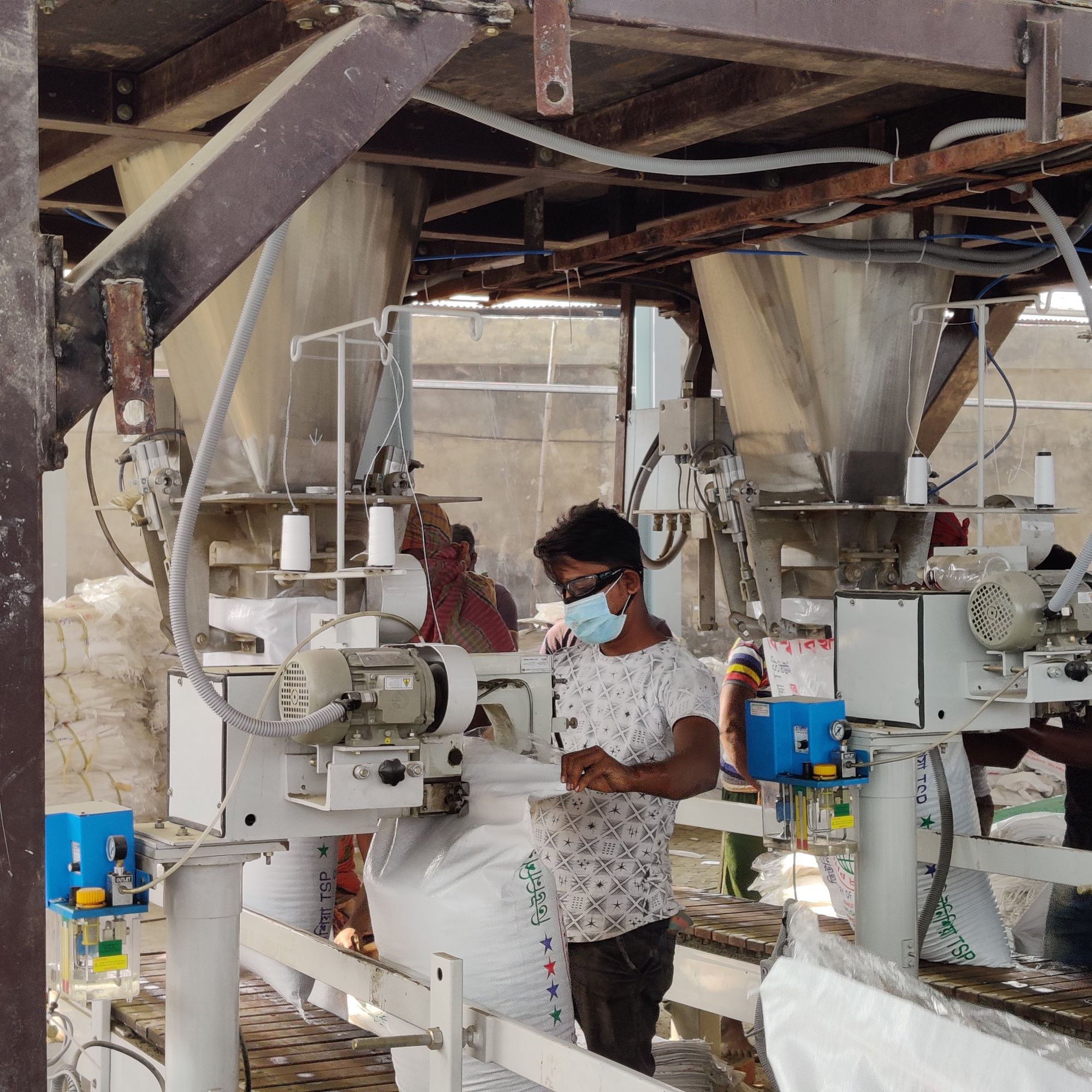 Operator at an automatic filling spout with a 50 kg HDPE bag being filled below the weigh hopper