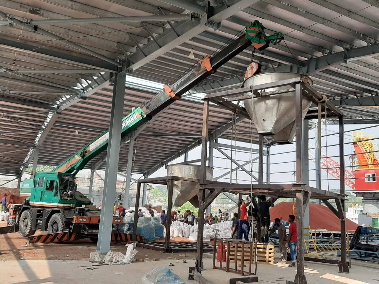 Mobile crane lifting a fabricated hopper cone into position on the plant structure