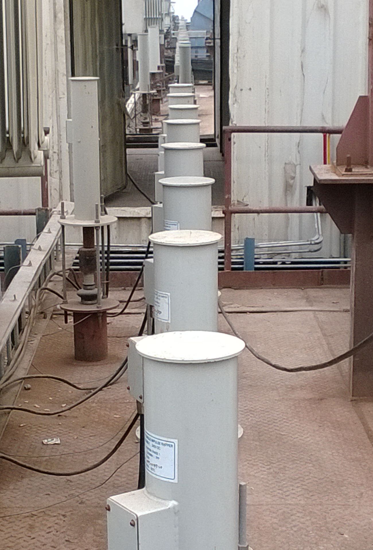 Close view of MIGI rapper coil housings with terminal boxes and cabling along an ESP roof walkway