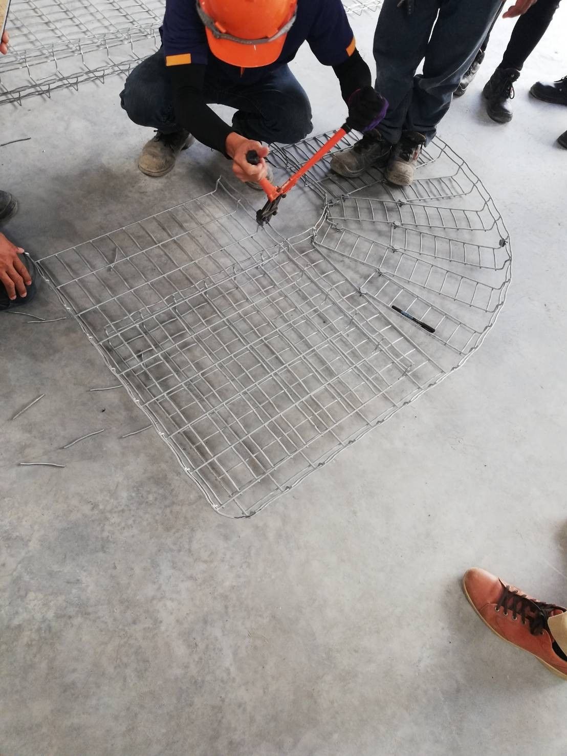 Installer cutting and forming a wire mesh tray bend on the floor with a hand cutting tool