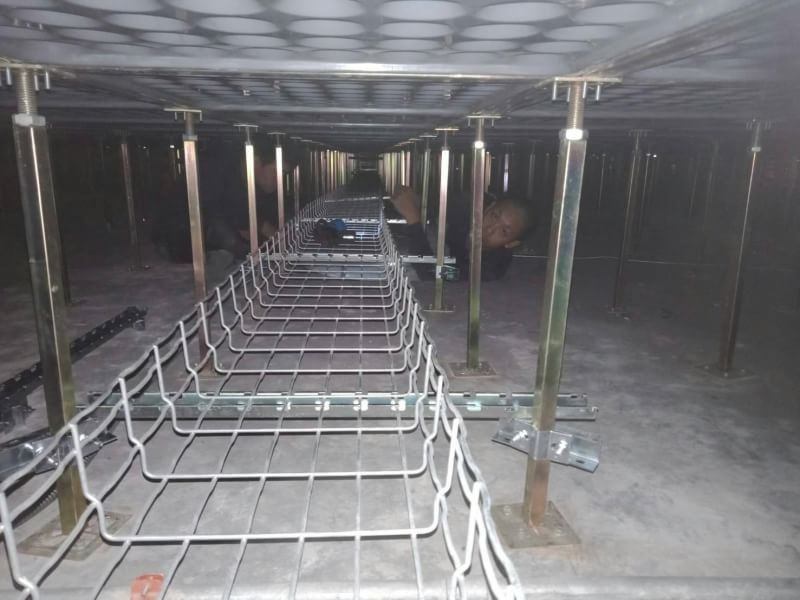 Wire mesh cable tray run being assembled on pedestal supports beneath a raised floor